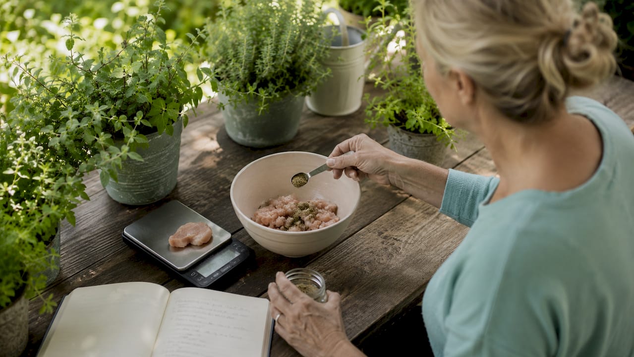 Woman preparing homemade dog food weighing ingredients