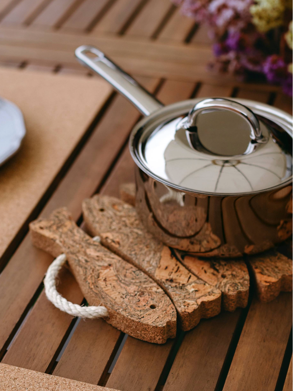 Cork placemats on a wooden table with plates and a pot.